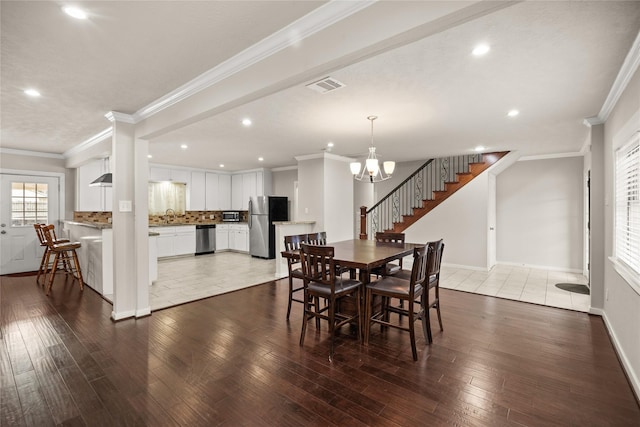 dining room featuring hardwood / wood-style flooring, crown molding, sink, and an inviting chandelier