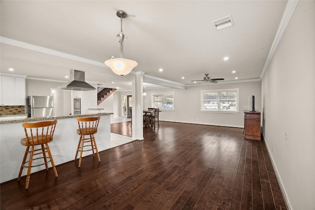 kitchen featuring white cabinetry, island range hood, appliances with stainless steel finishes, dark hardwood / wood-style floors, and light stone countertops