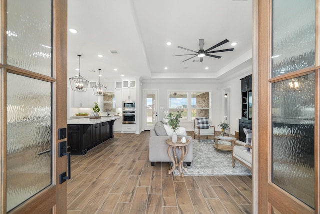 living room featuring sink, a raised ceiling, and ceiling fan