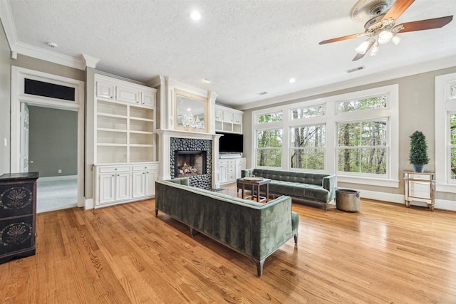 living room with ornamental molding, a fireplace, light hardwood / wood-style floors, and a textured ceiling