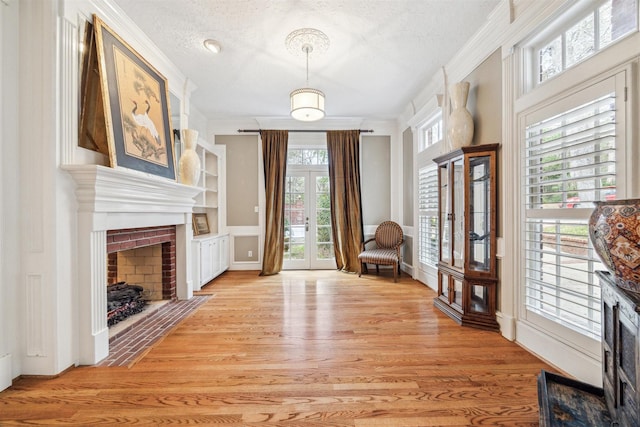 sitting room featuring a healthy amount of sunlight, ornamental molding, light hardwood / wood-style floors, and a textured ceiling