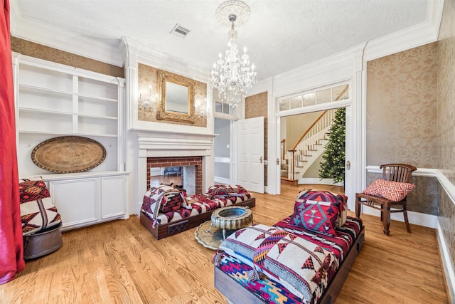 sitting room featuring crown molding, a fireplace, a textured ceiling, and light hardwood / wood-style flooring