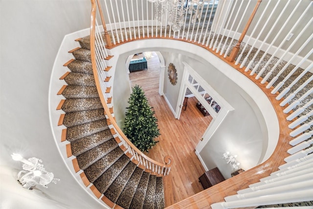 stairs with wood-type flooring and a towering ceiling