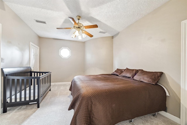 bedroom featuring ceiling fan, light carpet, and a textured ceiling