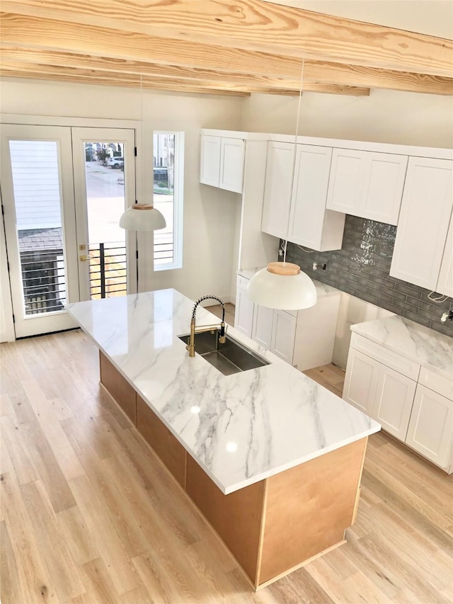2215 Bevis St, Houston, TX 77008 - kitchen with light stone countertops, light wood-type flooring, backsplash, and white cabinetry