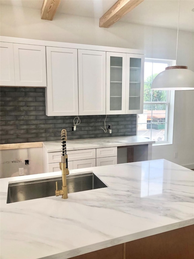 2215 Bevis St, Houston, TX 77008 - kitchen featuring beamed ceiling, backsplash, white cabinets, and light stone countertops