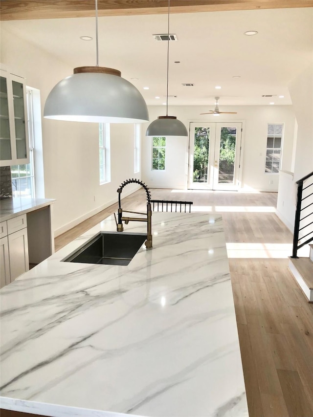 2215 Bevis St, Houston, TX 77008 - kitchen featuring light stone countertops, healthy amount of natural light, light wood-style floors, glass insert cabinets, and recessed lighting
