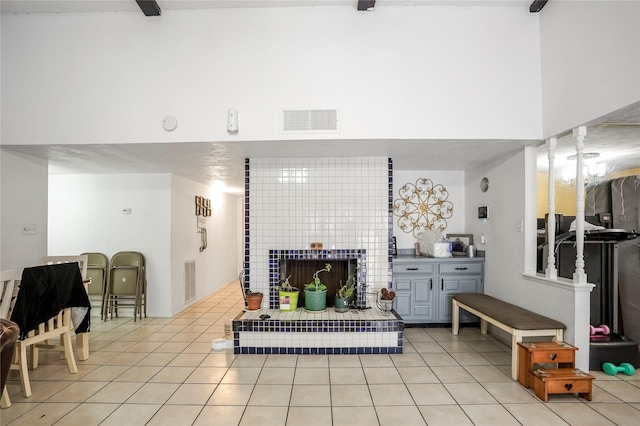 tiled living room featuring a towering ceiling and a fireplace