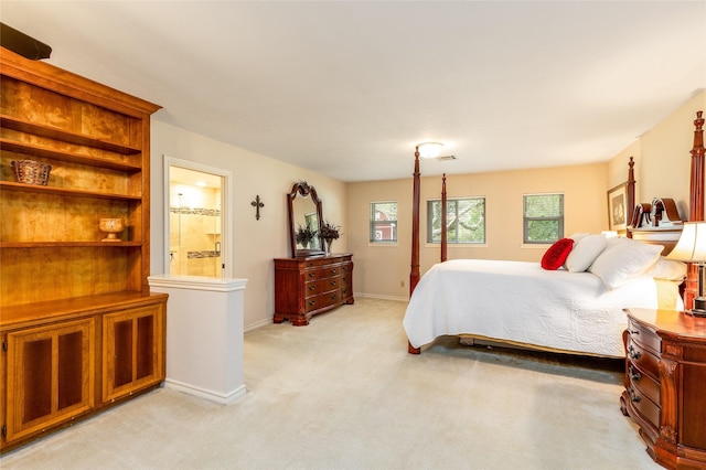 bedroom with light colored carpet, ensuite bath, and baseboards