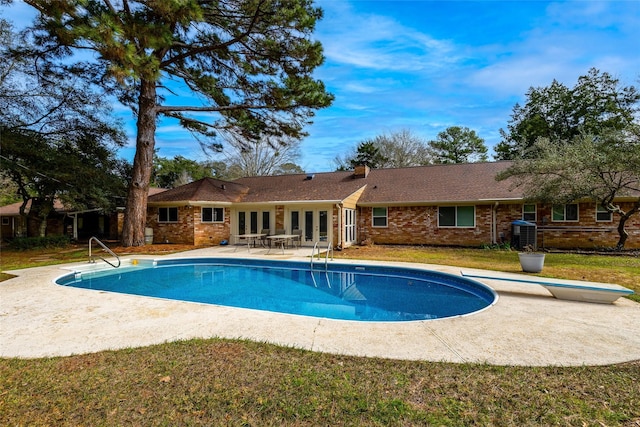 outdoor pool with a patio area, a diving board, french doors, and a yard