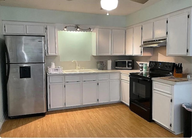 kitchen featuring white cabinetry, black / electric stove, sink, and stainless steel refrigerator