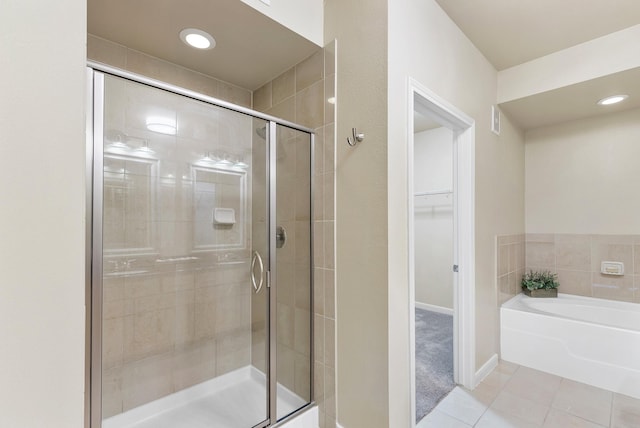 505 Jackson Hill St S Unit 108, Houston, TX 77007 - full bathroom featuring tile patterned floors, a shower stall, a garden tub, a spacious closet, and baseboards