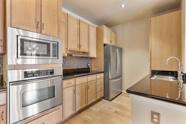 505 Jackson Hill St S Unit 108, Houston, TX 77007 - kitchen featuring appliances with stainless steel finishes, light brown cabinets, a sink, under cabinet range hood, and dark countertops