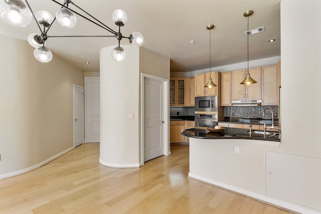 505 Jackson Hill St S Unit 108, Houston, TX 77007 - kitchen with stainless steel appliances, a sink, dark countertops, light wood-style floors, and backsplash