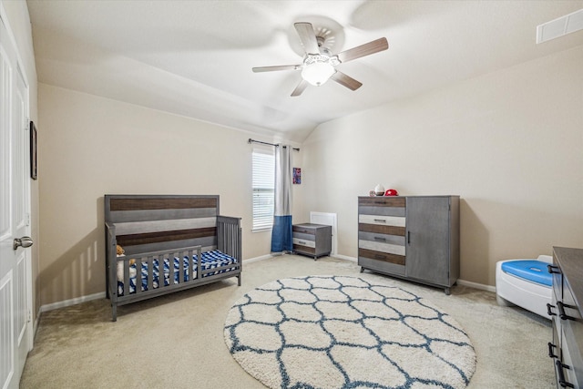 bedroom with a nursery area, visible vents, vaulted ceiling, and carpet flooring