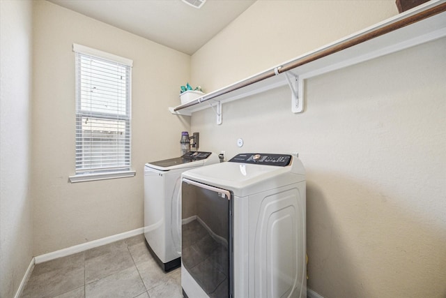 laundry room with laundry area, light tile patterned flooring, washing machine and dryer, and baseboards