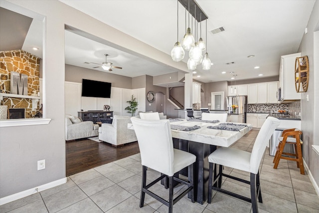 dining room with ceiling fan, light tile patterned floors, visible vents, and baseboards