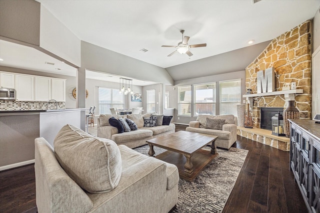 living room featuring dark wood-type flooring, a fireplace, a ceiling fan, baseboards, and vaulted ceiling