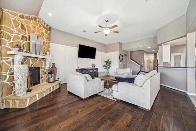 living area featuring ceiling fan, visible vents, a fireplace, and wood finished floors