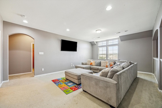 living room featuring visible vents, arched walkways, baseboards, and light colored carpet