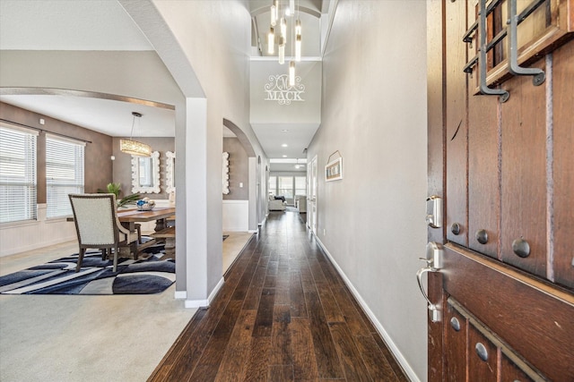 foyer entrance featuring dark wood-style floors, arched walkways, a wealth of natural light, and baseboards