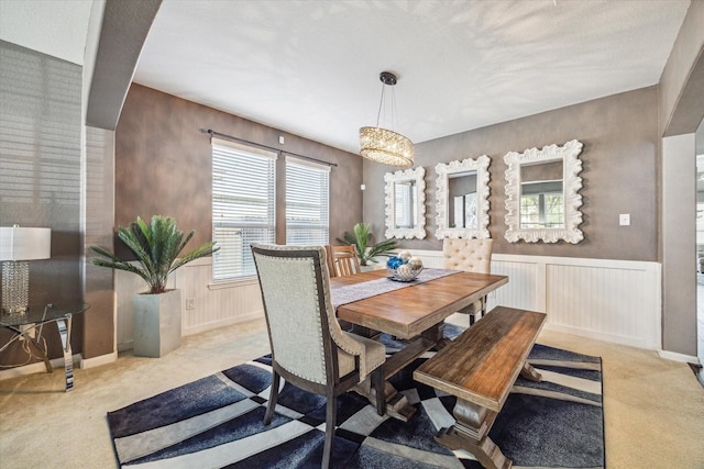 dining space featuring a wainscoted wall and light colored carpet