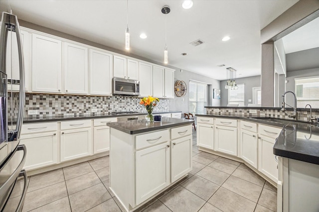 kitchen featuring appliances with stainless steel finishes, dark countertops, and decorative light fixtures