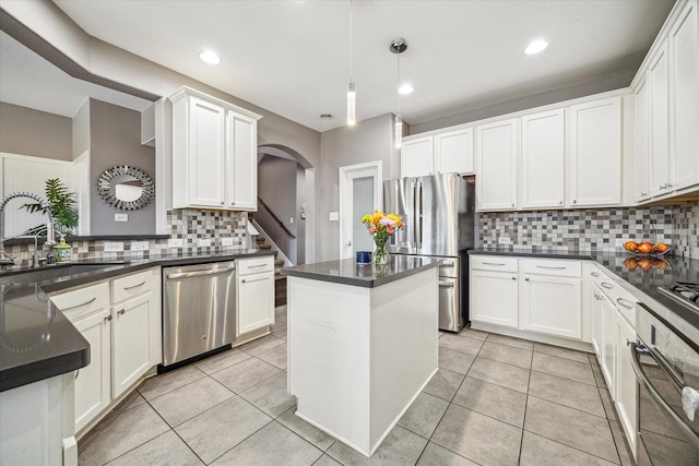 kitchen featuring appliances with stainless steel finishes, dark countertops, pendant lighting, and a sink