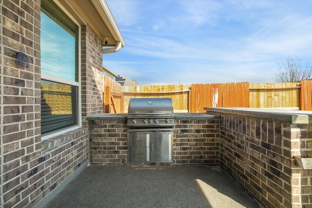 view of patio featuring a grill, an outdoor kitchen, and fence