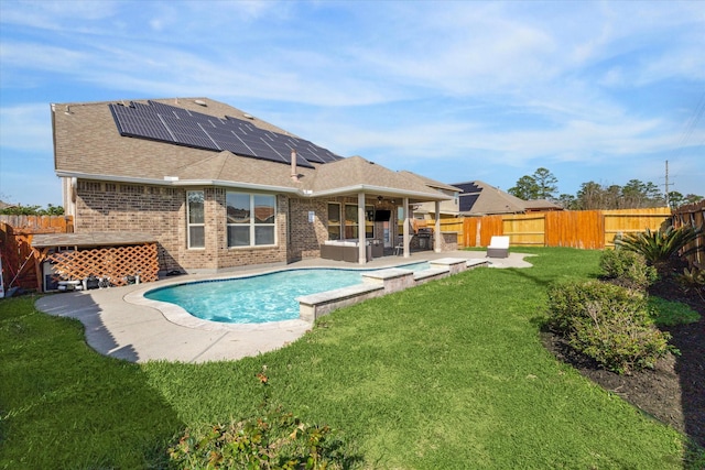 rear view of property with a fenced backyard, solar panels, brick siding, a lawn, and a fenced in pool