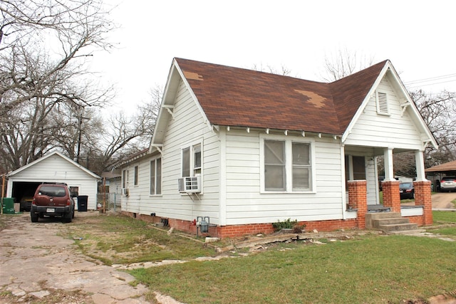 view of front facade with covered porch, an outbuilding, cooling unit, a garage, and a front lawn