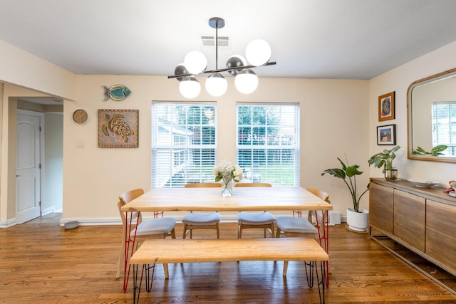 dining area with plenty of natural light, hardwood / wood-style floors, and a chandelier