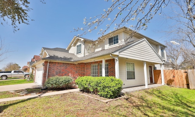 view of front of property with an attached garage, brick siding, fence, concrete driveway, and a front lawn