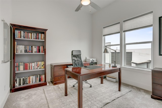 home office with light carpet, a ceiling fan, and baseboards