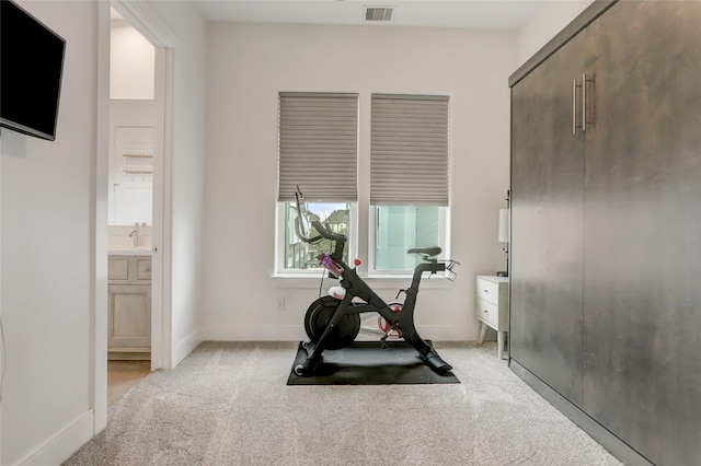 workout area with baseboards, visible vents, and light colored carpet