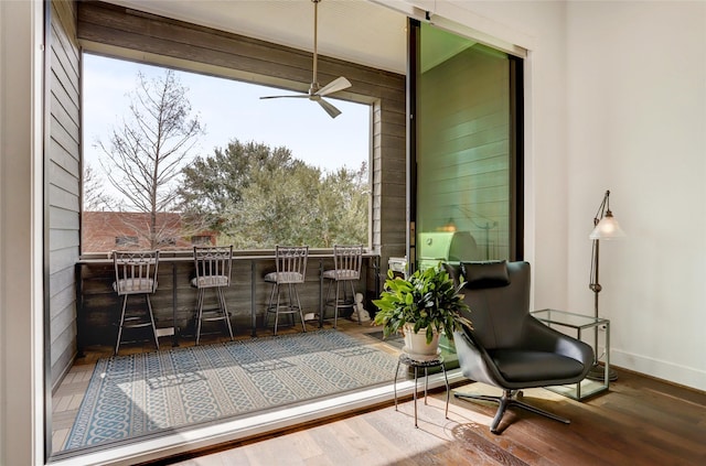 interior space featuring a dry bar, ceiling fan, baseboards, and wood finished floors