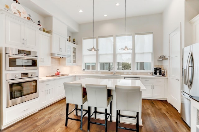 kitchen with white cabinetry, a kitchen bar, appliances with stainless steel finishes, and a sink