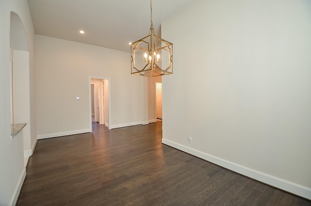 unfurnished room featuring dark wood-type flooring, a towering ceiling, and an inviting chandelier