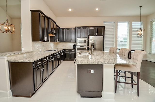 kitchen with stainless steel appliances, a breakfast bar area, a notable chandelier, and decorative light fixtures