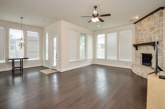 unfurnished living room featuring a stone fireplace, dark hardwood / wood-style flooring, and ceiling fan with notable chandelier