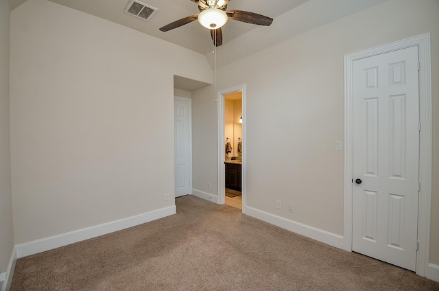 unfurnished bedroom with vaulted ceiling, connected bathroom, light colored carpet, and ceiling fan