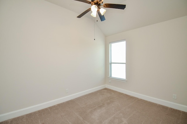 spare room featuring ceiling fan, light colored carpet, and vaulted ceiling