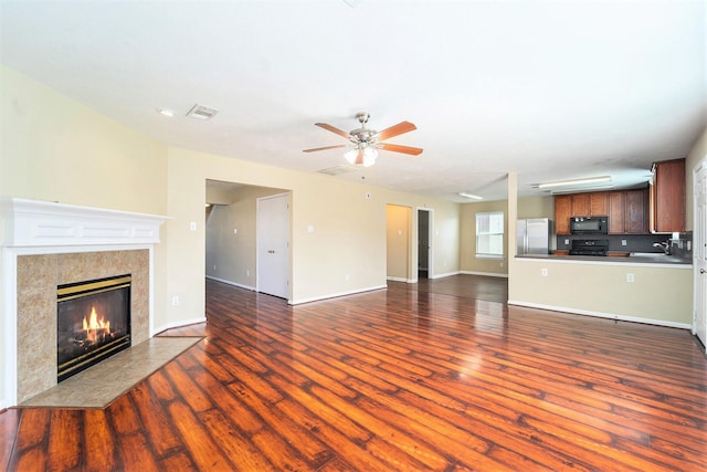 unfurnished living room with a ceiling fan, dark wood-style flooring, a fireplace, and baseboards