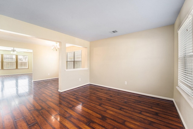 spare room featuring baseboards, visible vents, dark wood-type flooring, and a wealth of natural light