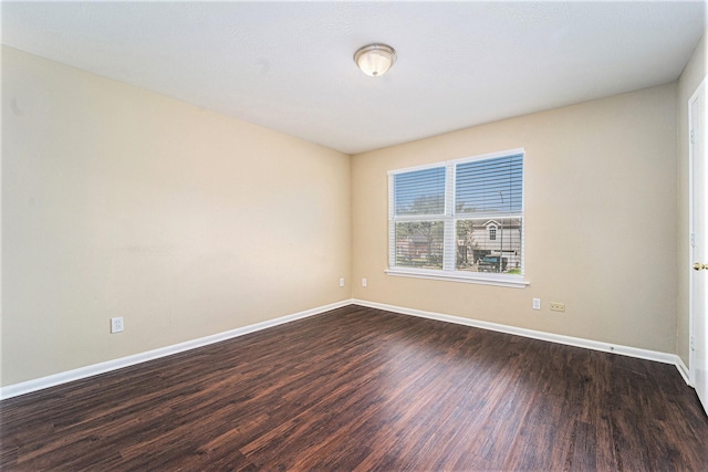 unfurnished room with baseboards and dark wood finished floors