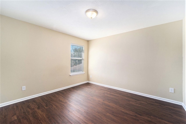 spare room featuring baseboards and dark wood-style flooring