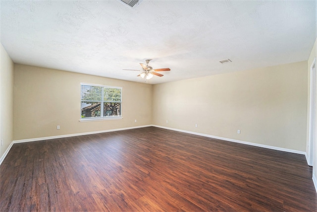 unfurnished room with a ceiling fan, dark wood-style flooring, a textured ceiling, and baseboards