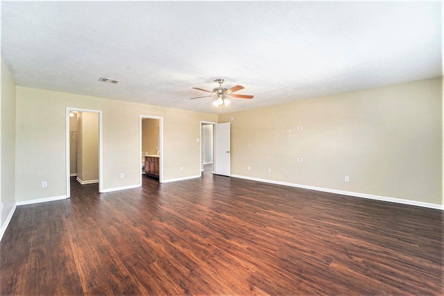 empty room featuring dark wood-style flooring, visible vents, ceiling fan, and baseboards