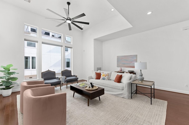 living room with ceiling fan, light hardwood / wood-style floors, and a high ceiling