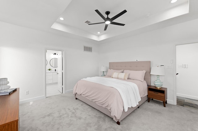 bedroom featuring light carpet, a raised ceiling, ceiling fan, and ensuite bathroom